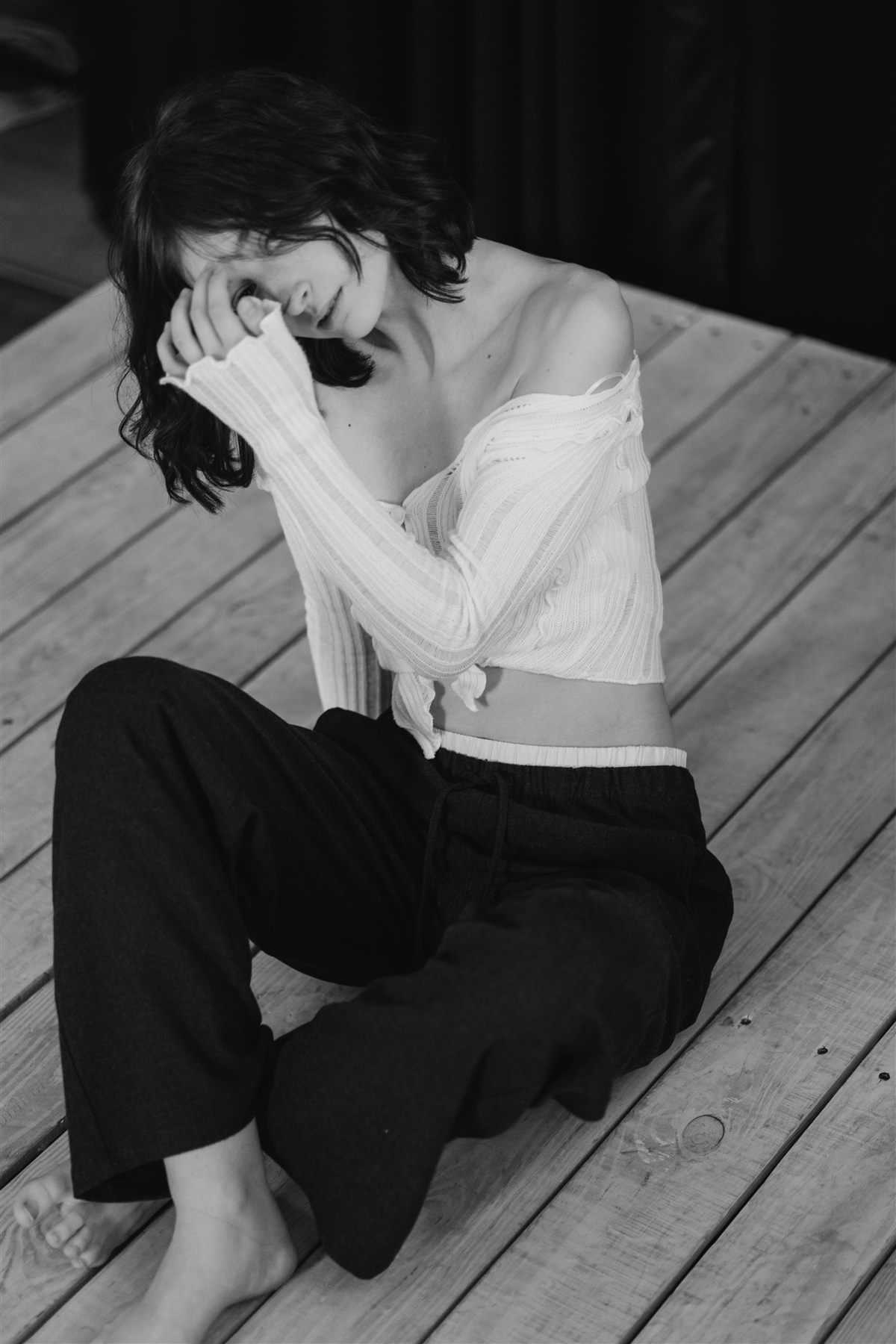 Candid black and white photo of Arina Mura seated on a wooden floor